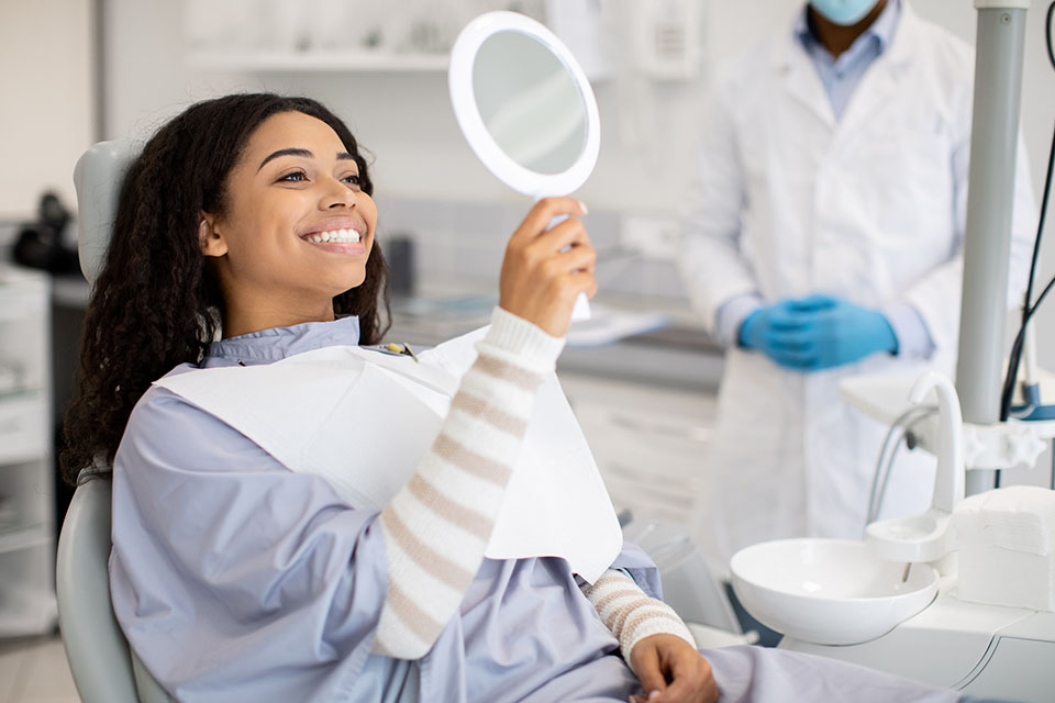 Happy woman looking in a mirror after orthodontic treatment.