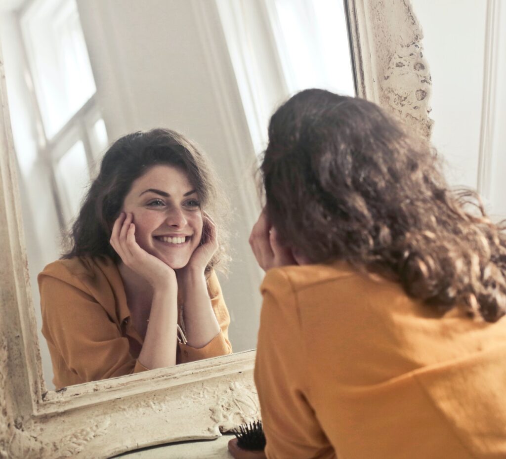 woman looking at her perfect smile in the mirror knowing braces can improve health
