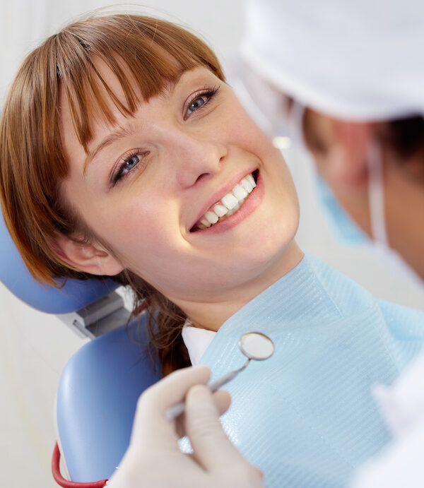 woman in orthodontics chair smiling because braces can improve health